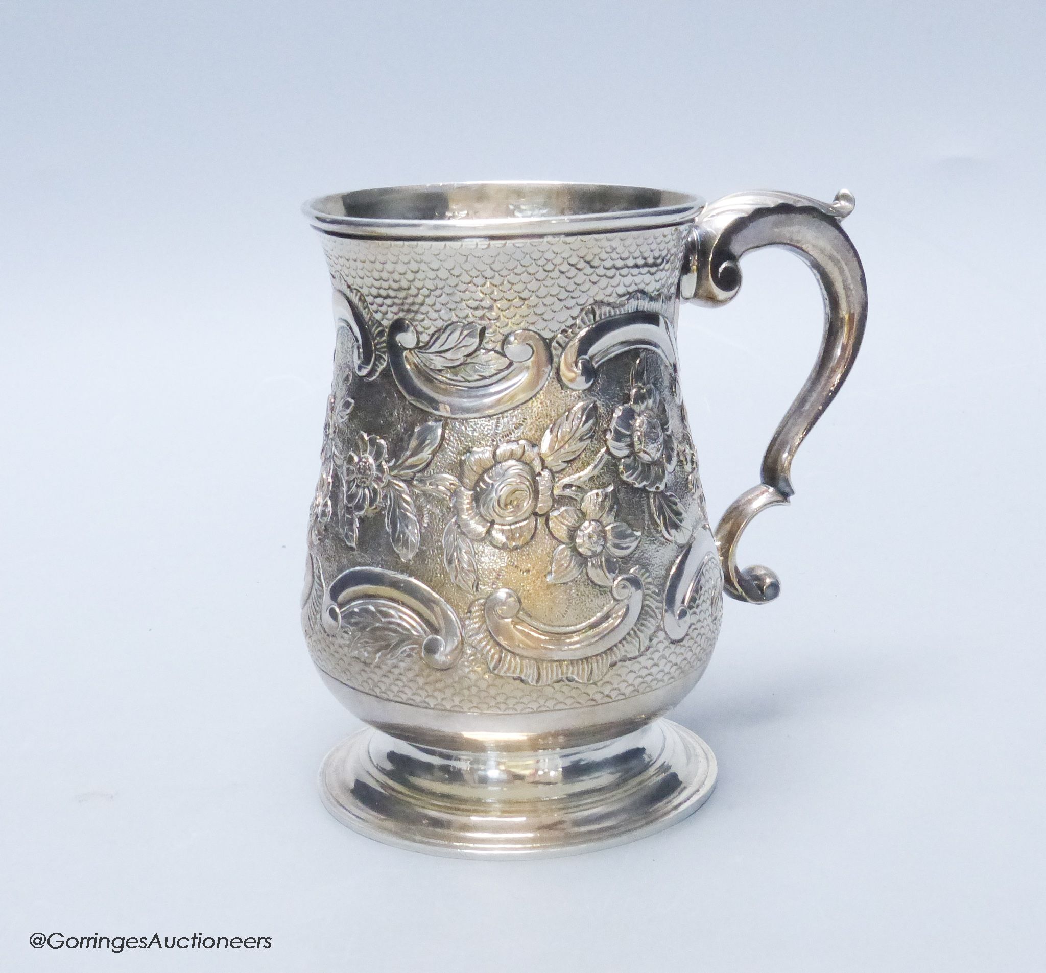 A George III silver baluster mug, with later embossed decoration, London, 1770, 12.7cm, 12.5 oz, indistinct maker's mark.